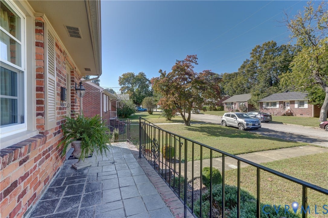409 Lilliston Avenue, Colonial Heights, VA 23834 Exterior covered porch featuring brick masonry siding, flagstone flooring, and black wrought-iron railing