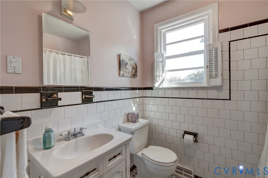 409 Lilliston Avenue, Colonial Heights, VA 23834 Bathroom featuring white wall tile with black trim, a vanity with an integrated sink, polished metal faucet hardware, and a window with plantation shutters
