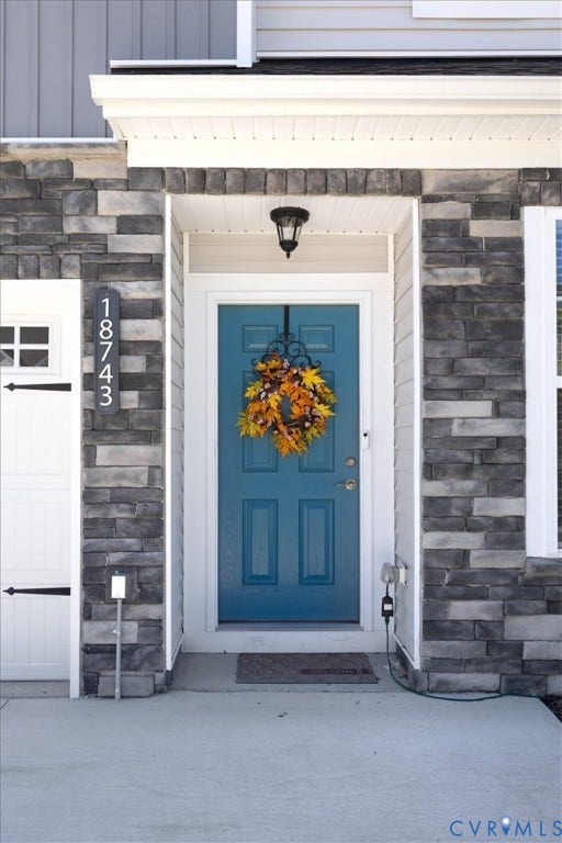18743 Palisades Ridge, Palisades Cove, Moseley, VA 23120 Covered entryway featuring a stone veneer facade, a panelized door with a metallic handle set, and a built-in overhead light fixture