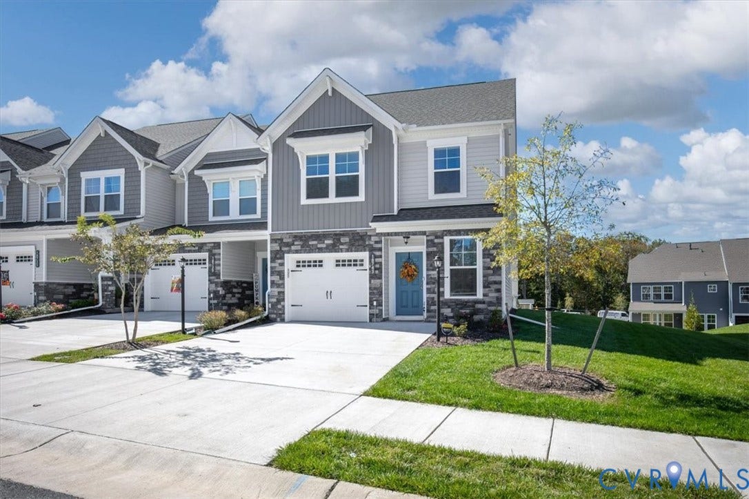 18743 Palisades Ridge, Palisades Cove, Moseley, VA 23120 Multi-level townhome exterior featuring gray horizontal siding, stone veneer accents, an attached single-car garage, and asphalt shingle roofing