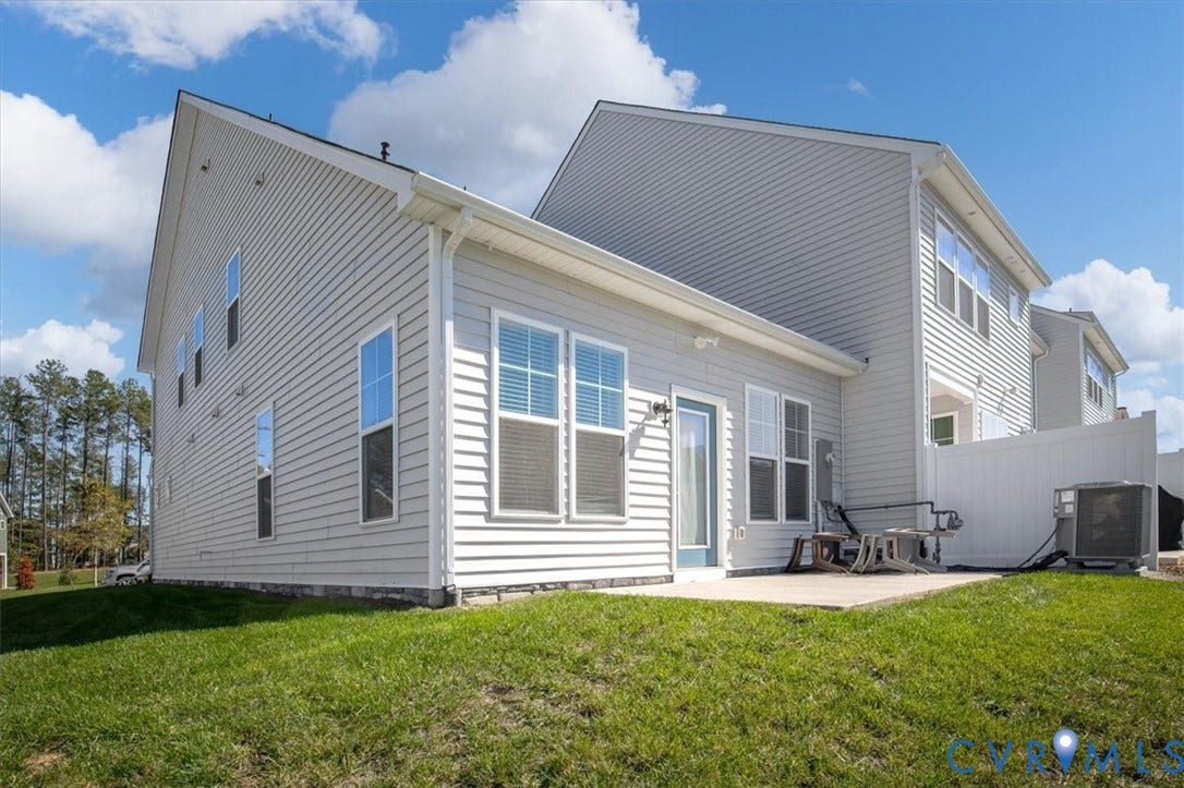 18743 Palisades Ridge, Palisades Cove, Moseley, VA 23120 Rear exterior featuring light gray horizontal siding, a concrete patio, multi-pane windows, and a white privacy fence
