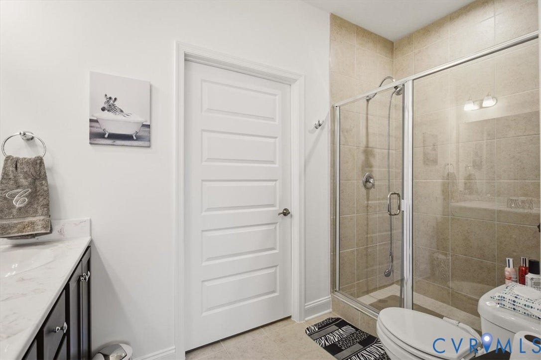 18743 Palisades Ridge, Palisades Cove, Moseley, VA 23120 Bathroom featuring a vanity with stone-finish countertop and undermount sink, a tiled walk-in shower with glass enclosure, and a five-panel interior door