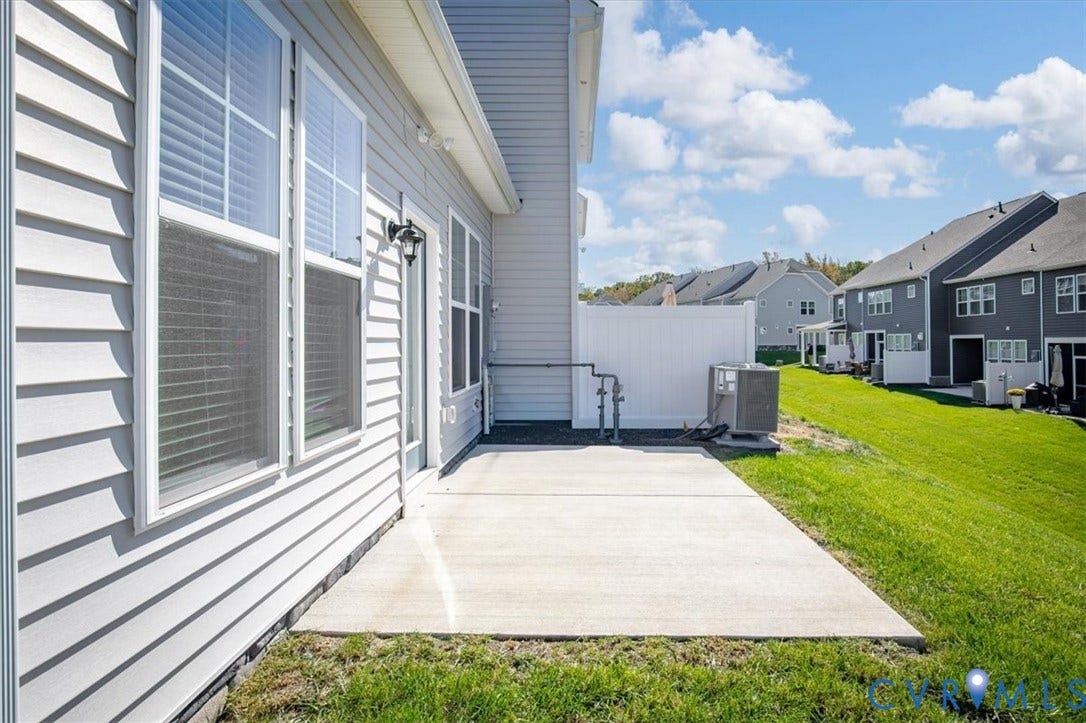 18743 Palisades Ridge, Palisades Cove, Moseley, VA 23120 Exterior elevation featuring light-colored horizontal lap siding, a concrete patio, and a white vinyl privacy fence