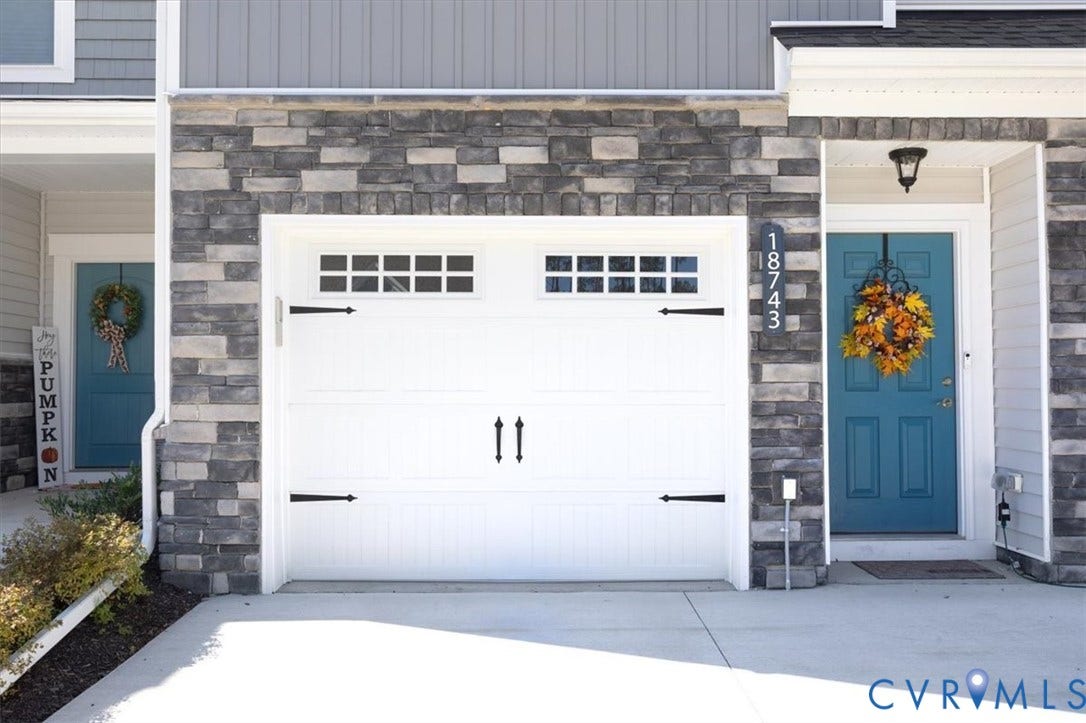18743 Palisades Ridge, Palisades Cove, Moseley, VA 23120 Exterior facade featuring stacked stone veneer, white garage door with decorative hardware and transom windows, and teal-painted entry door