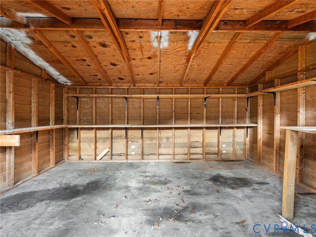 5504 Chanson Road, Salem Woods, North Chesterfield, VA 23237 Enclosed storage structure featuring exposed timber framing, concrete flooring, and multiple built-in wood-plank shelving units