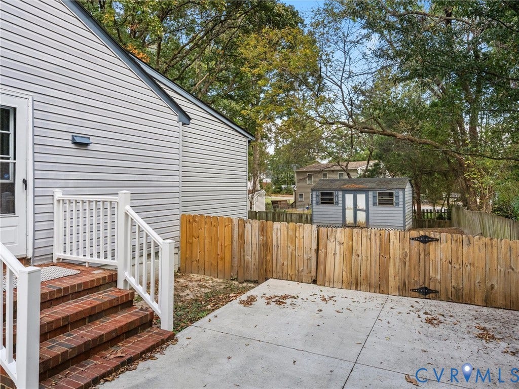 5504 Chanson Road, Salem Woods, North Chesterfield, VA 23237 Exterior area featuring a concrete patio, red brick steps, white railing, wood fence, and a detached storage structure