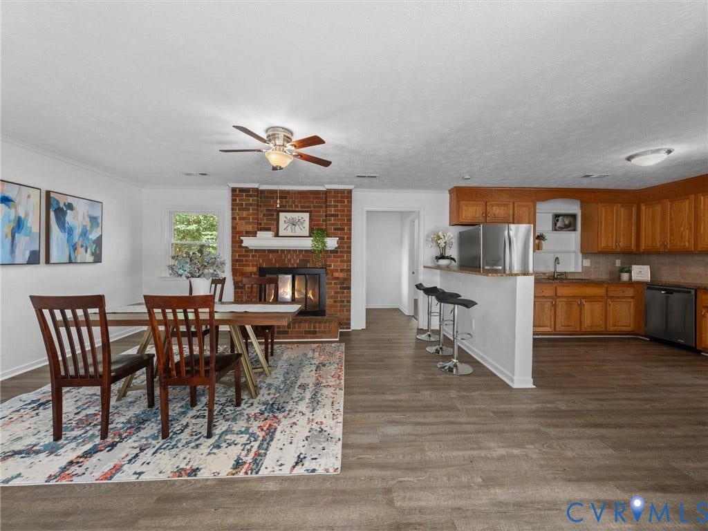5504 Chanson Road, Salem Woods, North Chesterfield, VA 23237 Open concept space featuring wood-finish flooring, a full-height brick fireplace, a kitchen island with a breakfast bar, and wood cabinetry