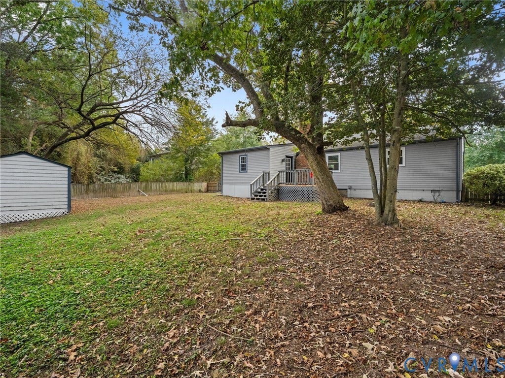 5504 Chanson Road, Salem Woods, North Chesterfield, VA 23237 Expansive backyard featuring mature trees, a detached storage structure, wooden rear deck with stairs, and a perimeter wood fence