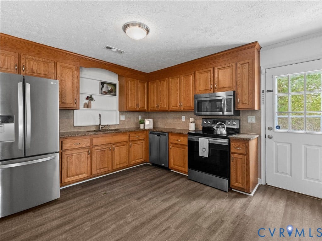 5504 Chanson Road, Salem Woods, North Chesterfield, VA 23237 Kitchen featuring wood-finish cabinetry, stone-surface countertops, stainless steel appliances, recessed shelving, and wood-finish flooring