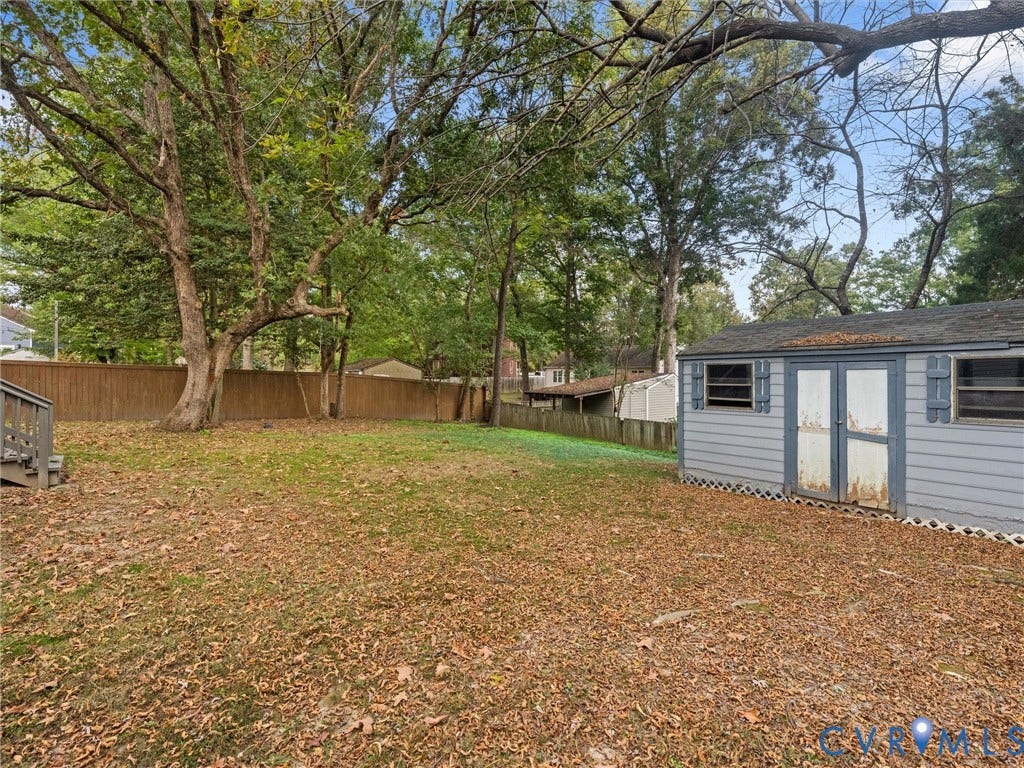 5504 Chanson Road, Salem Woods, North Chesterfield, VA 23237 Backyard featuring a wood privacy fence, mature trees, and a detached storage shed with louvered shutters