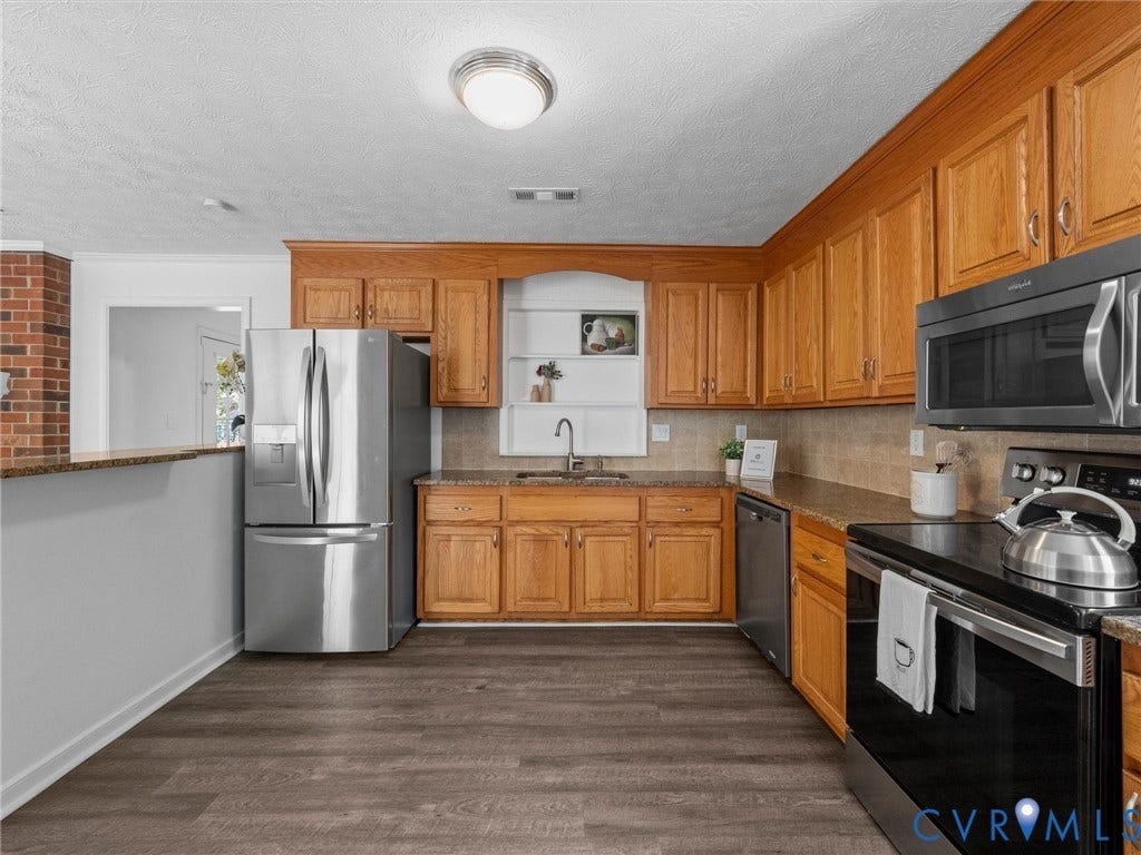 5504 Chanson Road, Salem Woods, North Chesterfield, VA 23237 Kitchen featuring oak cabinetry, wood-finish flooring, stone-surfaced countertops, built-in stainless steel appliances, and a recessed wall niche