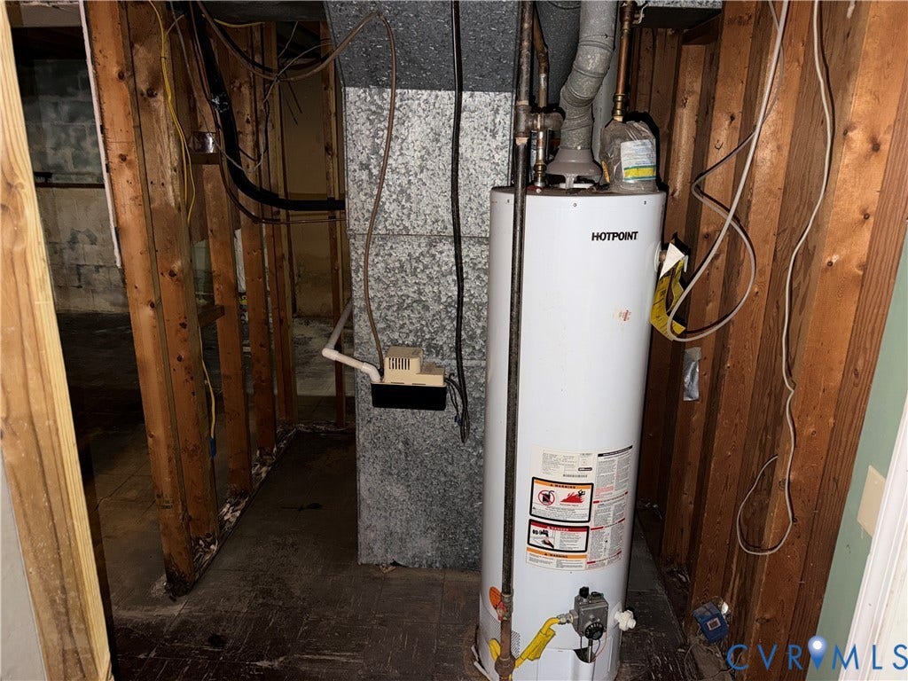 1513 West Lane, Petersburg, VA 23803 Hotpoint water heater featuring metal flue venting, installed alongside a masonry chimney stack and exposed wood framing