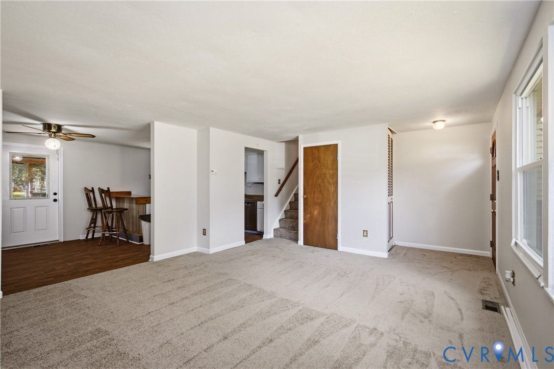 Interior space featuring neutral wall tones, carpeting, wood-finish flooring, a ceiling fan, and a built-in wooden door