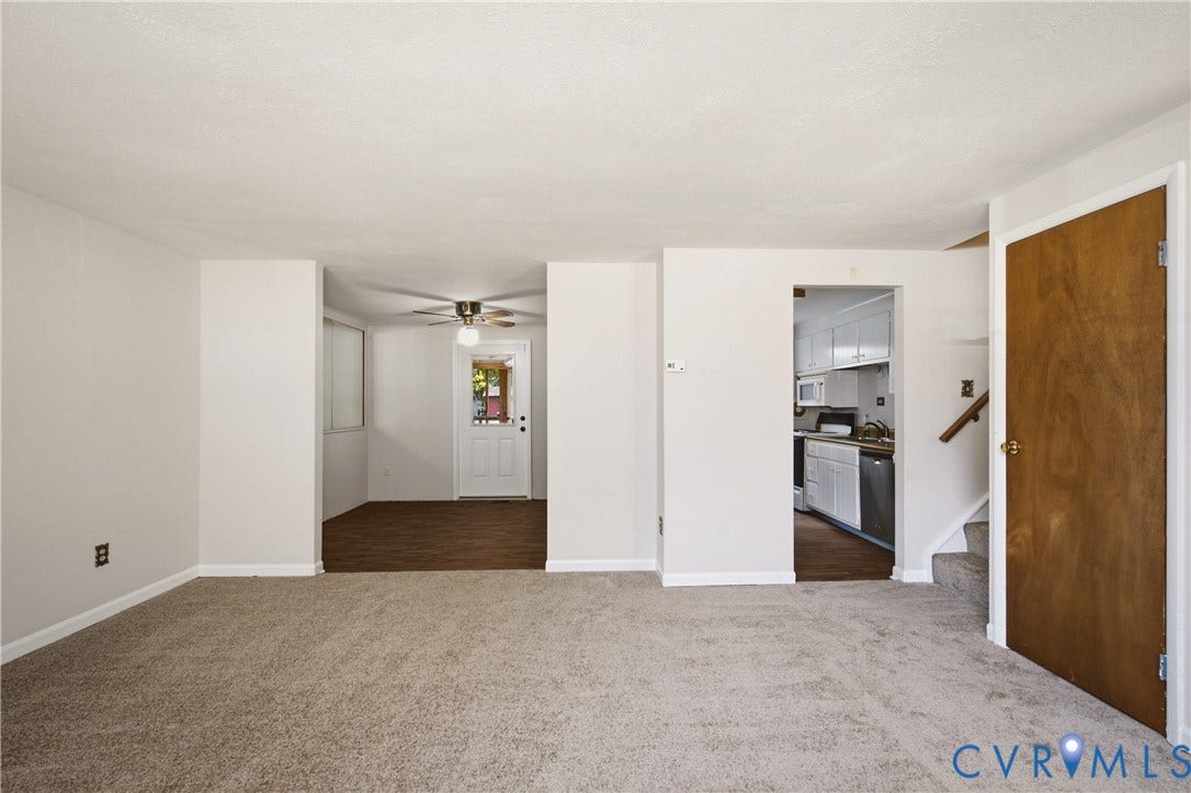 Neutral interior featuring neutral wall-to-wall carpeting, wood-finish flooring, a ceiling fan, and a wood-veneer interior door