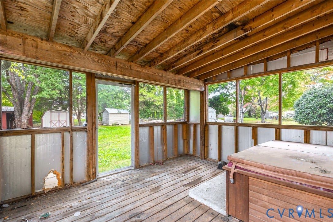 Enclosed porch featuring an exposed wood-beam ceiling, wood-plank flooring, and a built-in hot tub