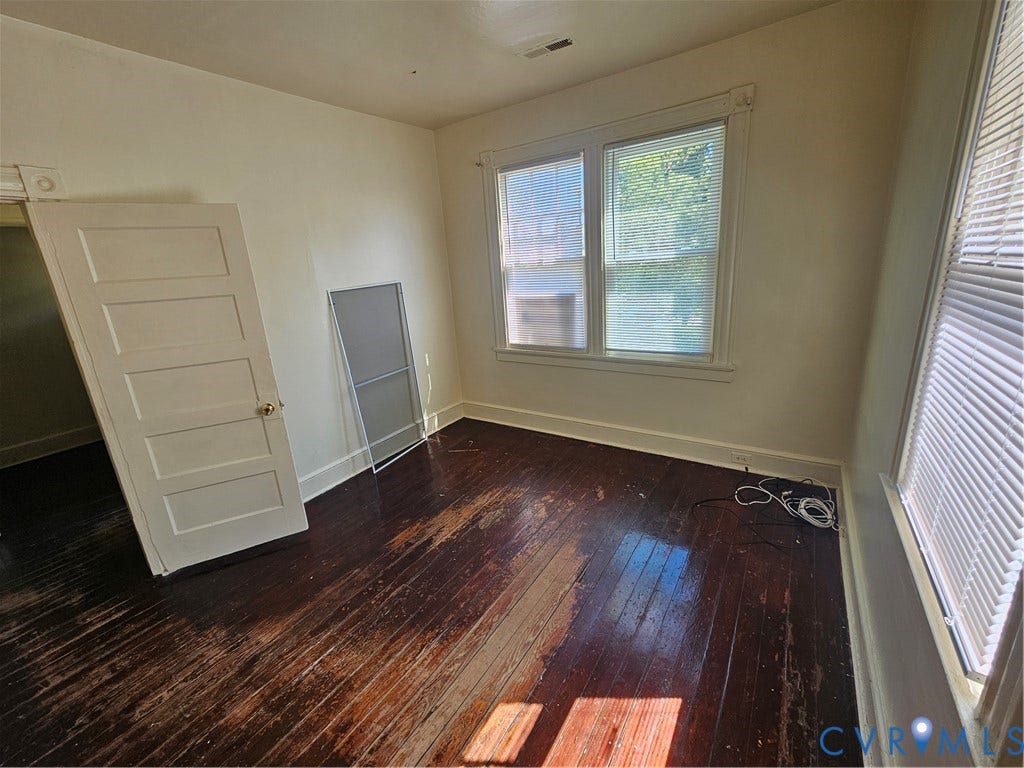 3503 Lawson Street, Richmond, VA 23224 Interior room featuring dark-stained hardwood flooring, multi-pane windows with trim casing, and a five-panel interior door