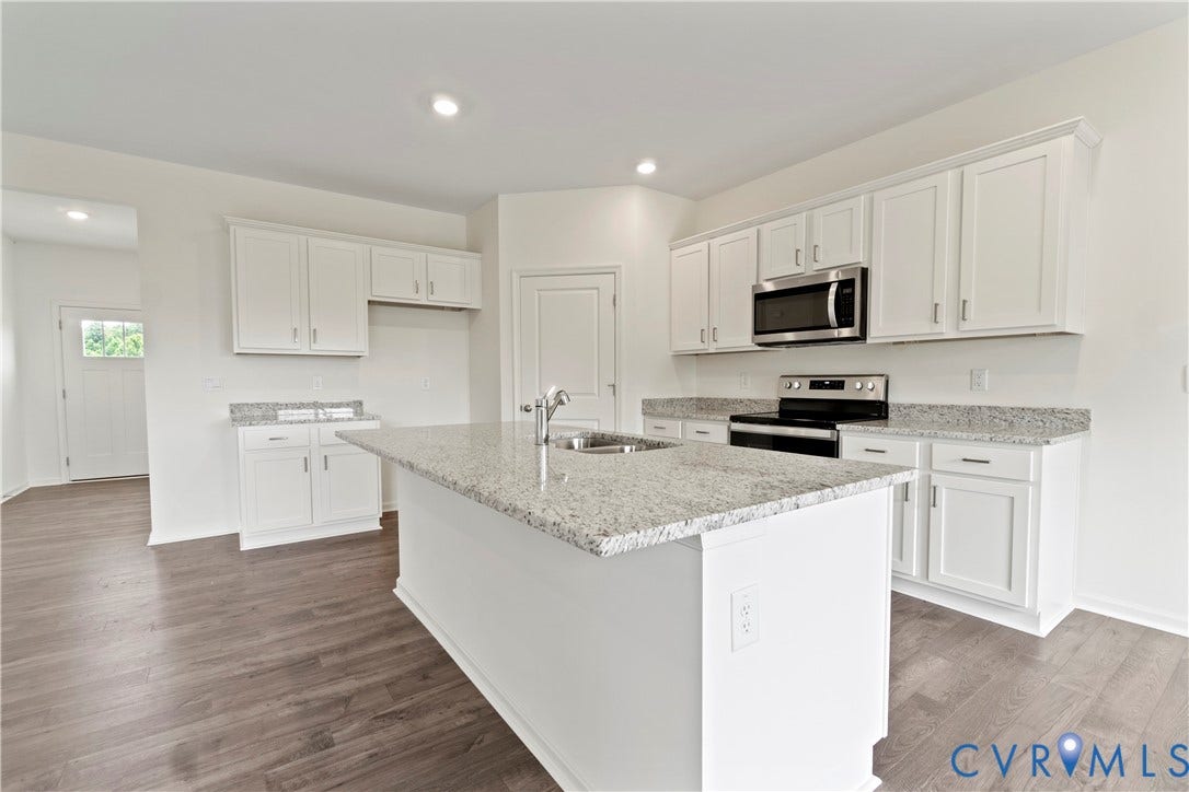 11231 Chappell Creek Circle, Chappell Creek, North Prince George, VA 23860 Modern kitchen featuring a central island with an undermount sink, granite-style countertops, white cabinetry, stainless steel appliances, and wood-finish flooring