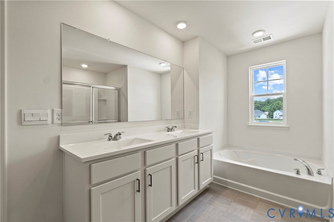 11231 Chappell Creek Circle, Chappell Creek, North Prince George, VA 23860 Bathroom featuring a dual vanity with white cabinetry and integrated sinks, a large wall-mounted mirror, a built-in bathtub with chrome fixtures, and a shower enclosure with sliding glass doors