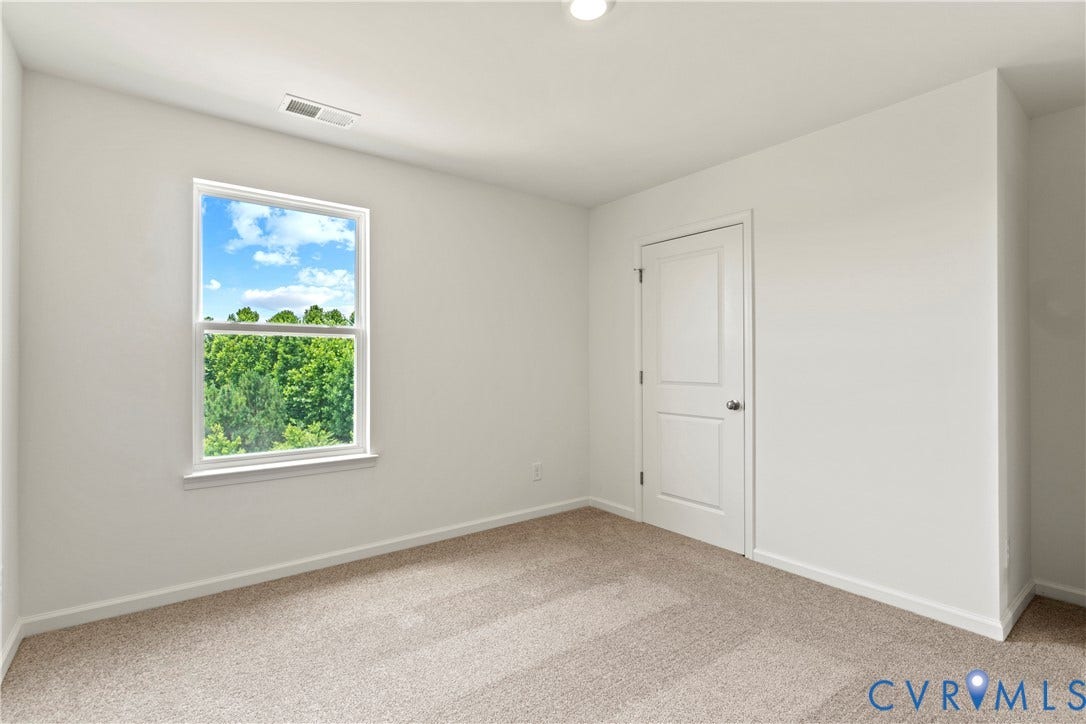 11231 Chappell Creek Circle, Chappell Creek, North Prince George, VA 23860 Light-filled interior space featuring a large window, neutral wall paint, and textured carpet flooring