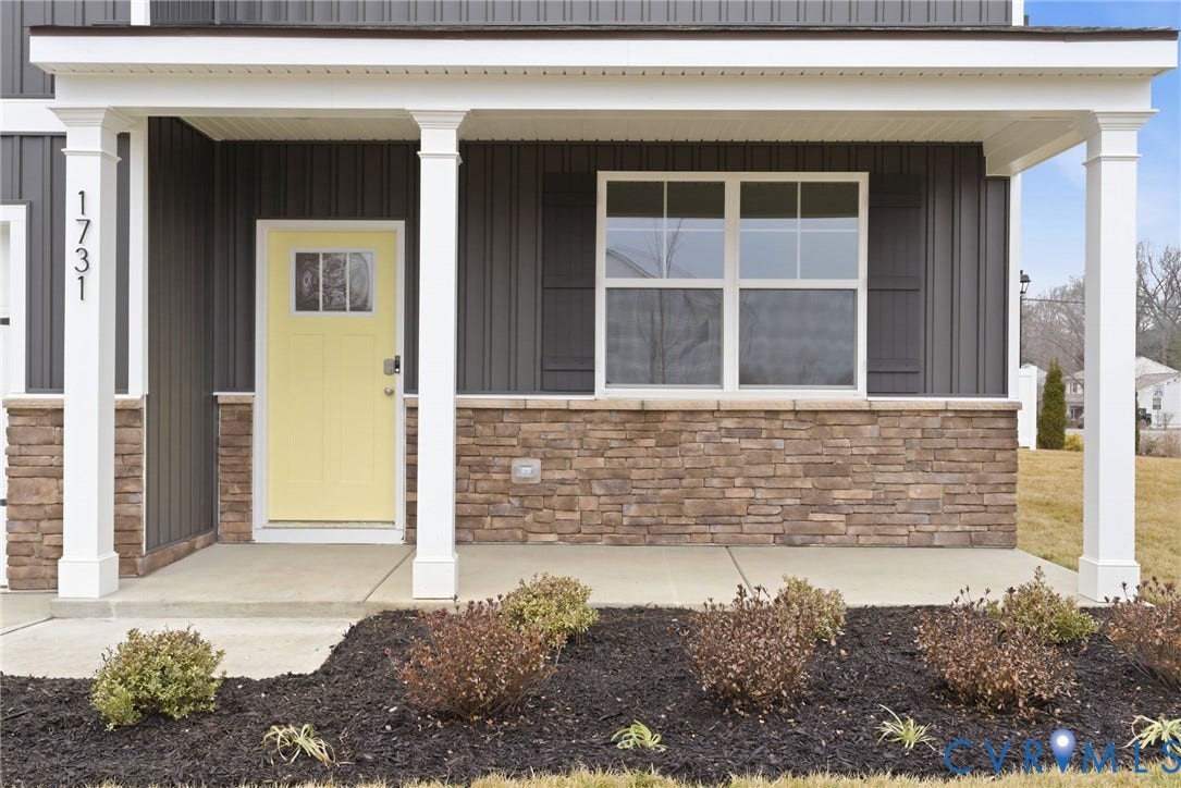 11231 Chappell Creek Circle, Chappell Creek, North Prince George, VA 23860 Inviting front porch featuring a vibrant yellow door with transom window detail, white architectural columns, dark vertical siding, and a stacked stone foundation