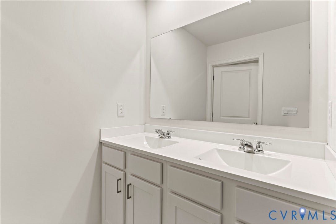 11231 Chappell Creek Circle, Chappell Creek, North Prince George, VA 23860 Double vanity featuring white cabinetry with shaker-style doors and dark hardware, integrated sinks, white countertops, and chrome faucets