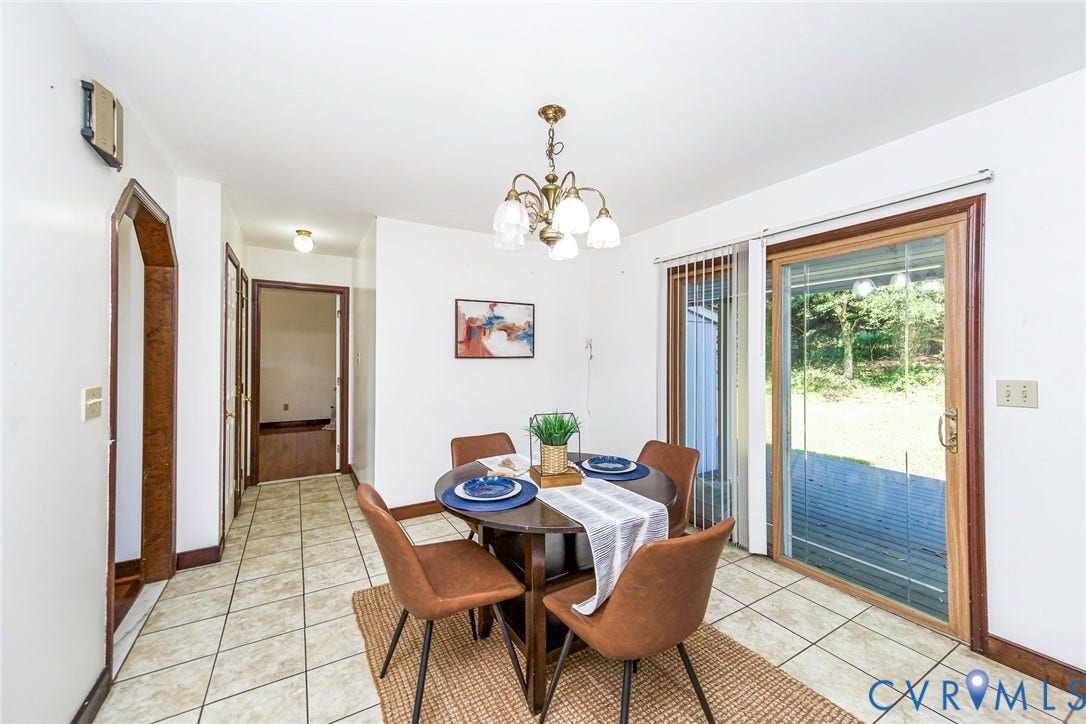 4124 Cogbill Road, Ampthill, VA 23234 Dining area featuring light-toned ceramic tile flooring, a multi-arm chandelier, an arched doorway, and sliding glass doors with dark wood-finish trim