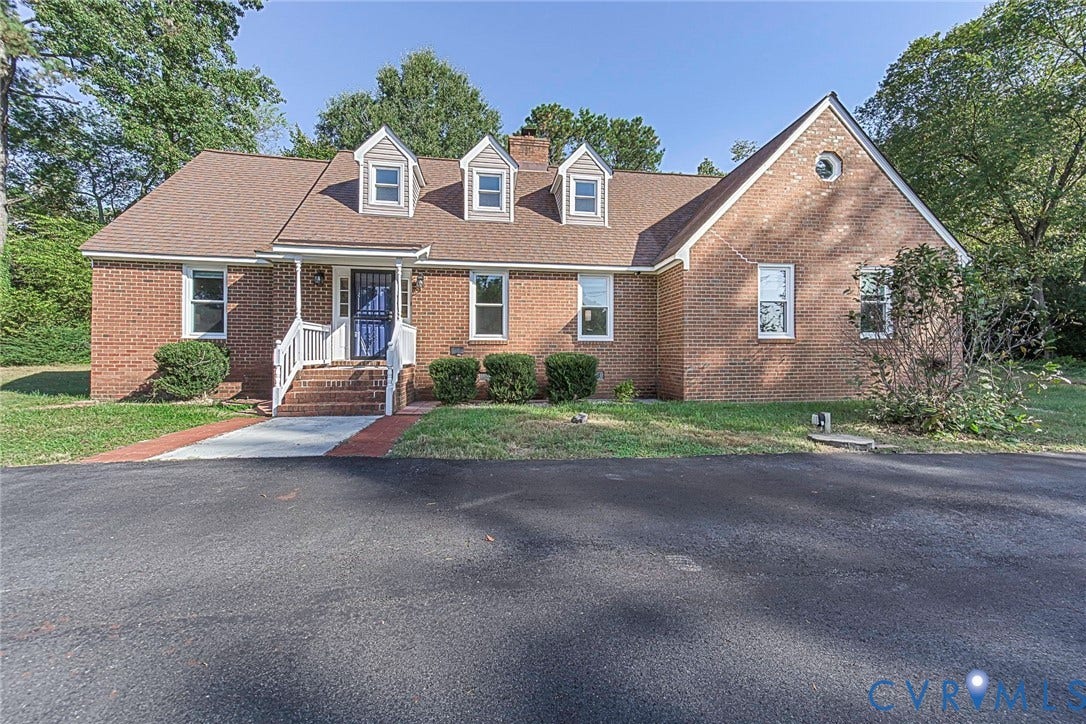 4124 Cogbill Road, Ampthill, VA 23234 Traditional brick exterior featuring three front-facing dormer windows, a steep-pitched roof, circular gable window, and a paved brick walkway