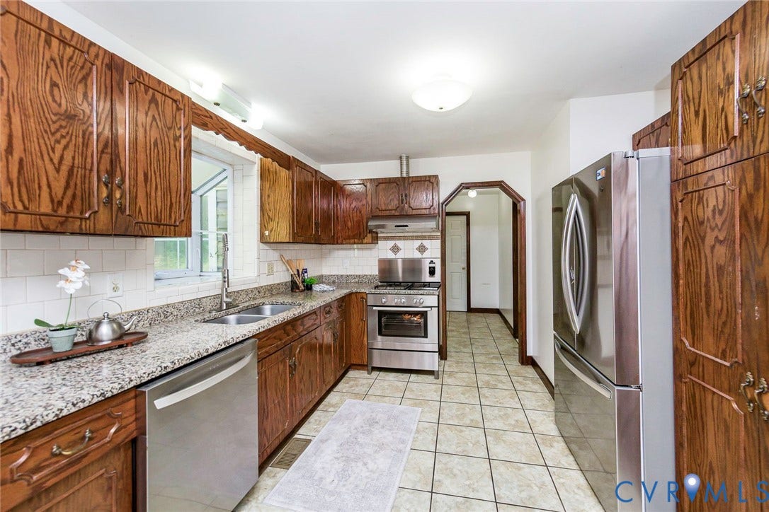 4124 Cogbill Road, Ampthill, VA 23234 Kitchen featuring stained wood cabinetry, stone-surface countertops, stainless steel appliances, ceramic tile backsplash, and tile flooring