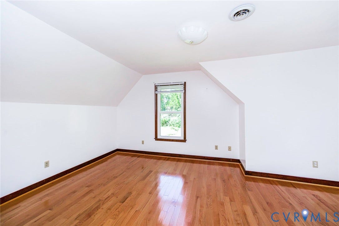 4124 Cogbill Road, Ampthill, VA 23234 Interior space featuring wood-finish flooring, a double-hung window with dark trim, sloped ceilings, and a flush-mount light fixture