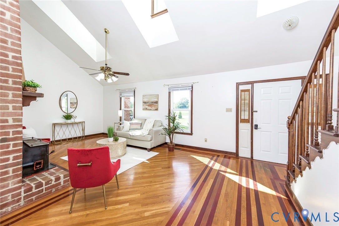 4124 Cogbill Road, Ampthill, VA 23234 Vaulted ceiling with skylights, exposed brick fireplace, inlaid wood-finish flooring, and open staircase with wooden banister