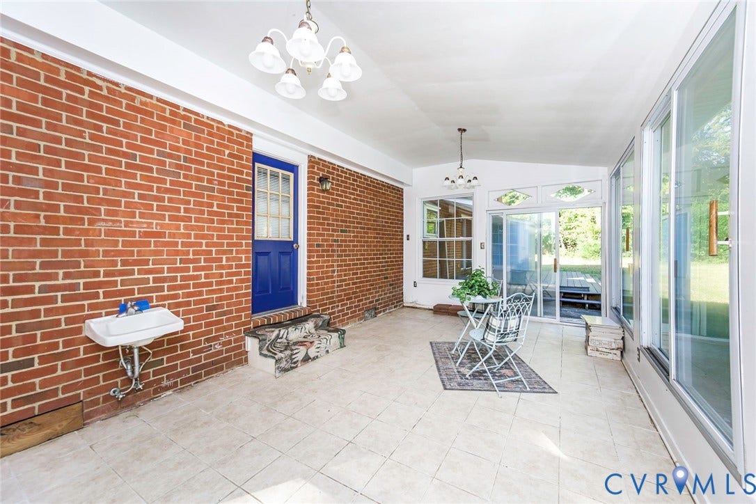 4124 Cogbill Road, Ampthill, VA 23234 Enclosed sunroom featuring exposed brick walls, tile flooring, large sliding glass doors, and two multi-arm light fixtures