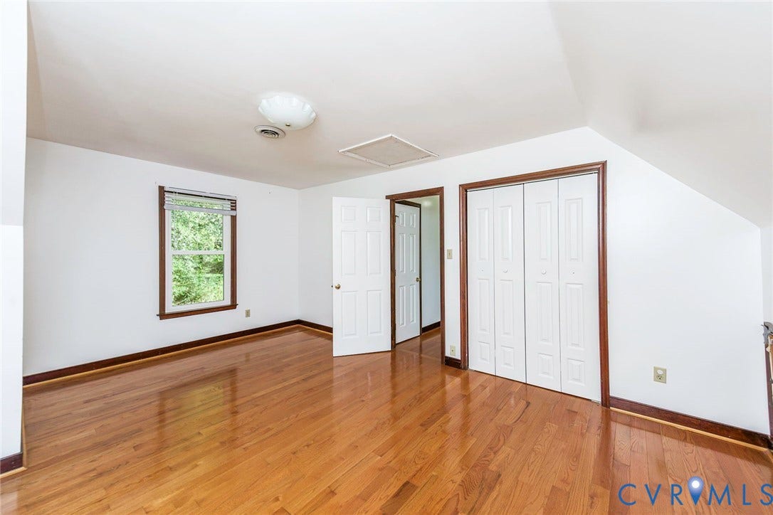 4124 Cogbill Road, Ampthill, VA 23234 Wood-finish flooring, white paneled interior doors, bifold closet doors, and multi-pane window with wood-finish trim