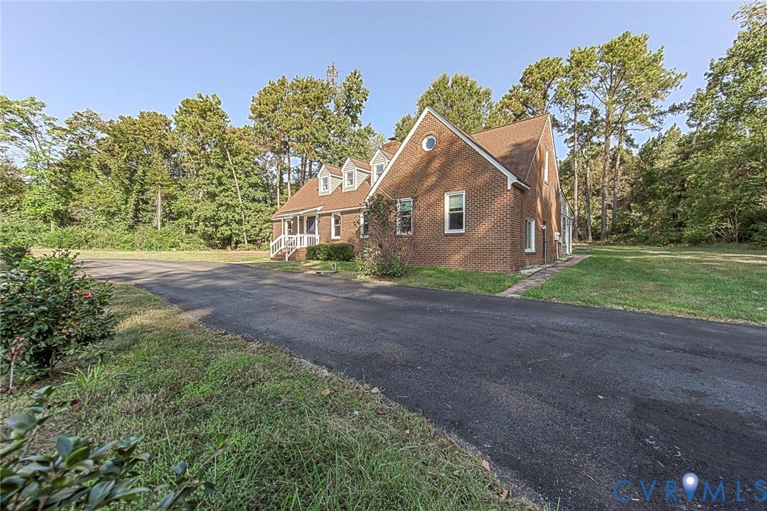 4124 Cogbill Road, Ampthill, VA 23234 Brick exterior featuring a gabled roofline, dormer windows, a circular gable vent, and an asphalt driveway