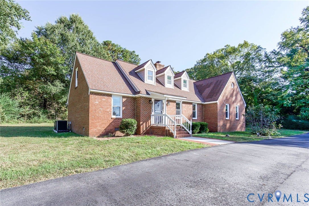 4124 Cogbill Road, Ampthill, VA 23234 Traditional brick exterior featuring three front-facing dormer windows, a steep-pitched roofline, and an asphalt driveway