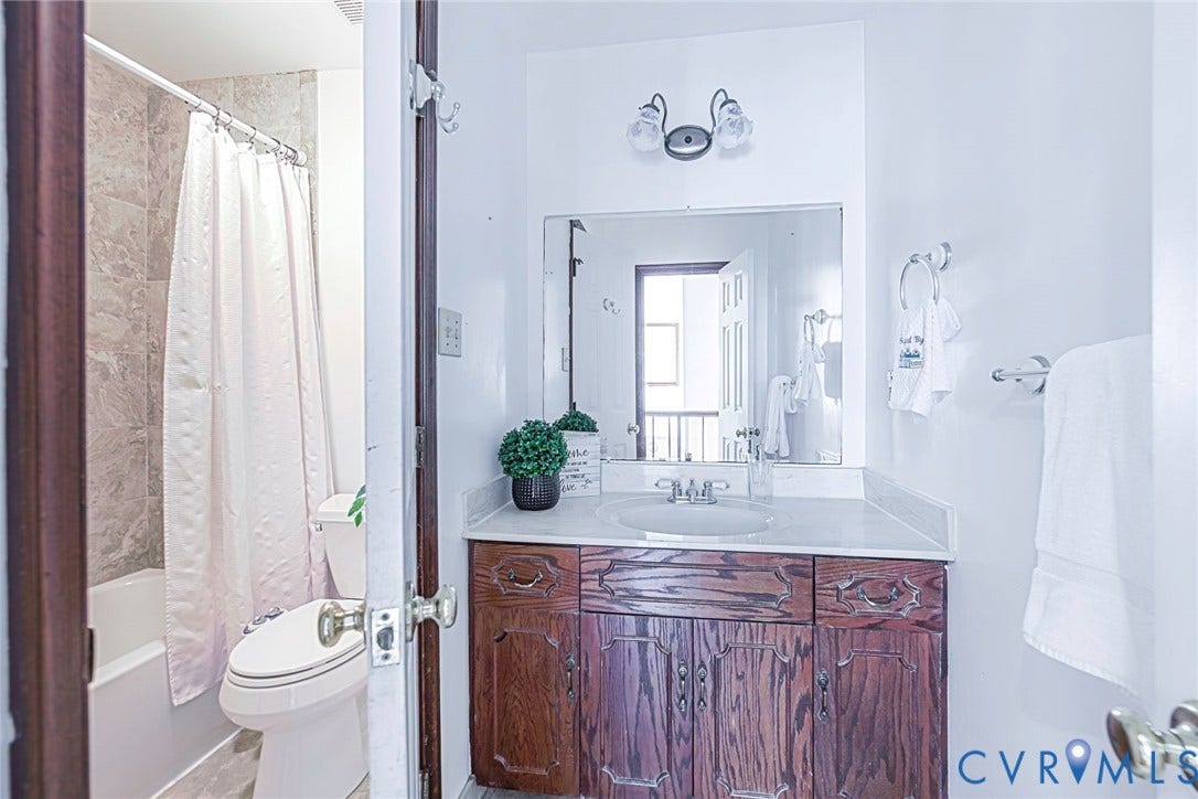 4124 Cogbill Road, Ampthill, VA 23234 Bathroom featuring a wood vanity with a solid-surface countertop, an integrated oval sink, a wall-mounted mirror, and a tub-shower combination with tile-surround walls