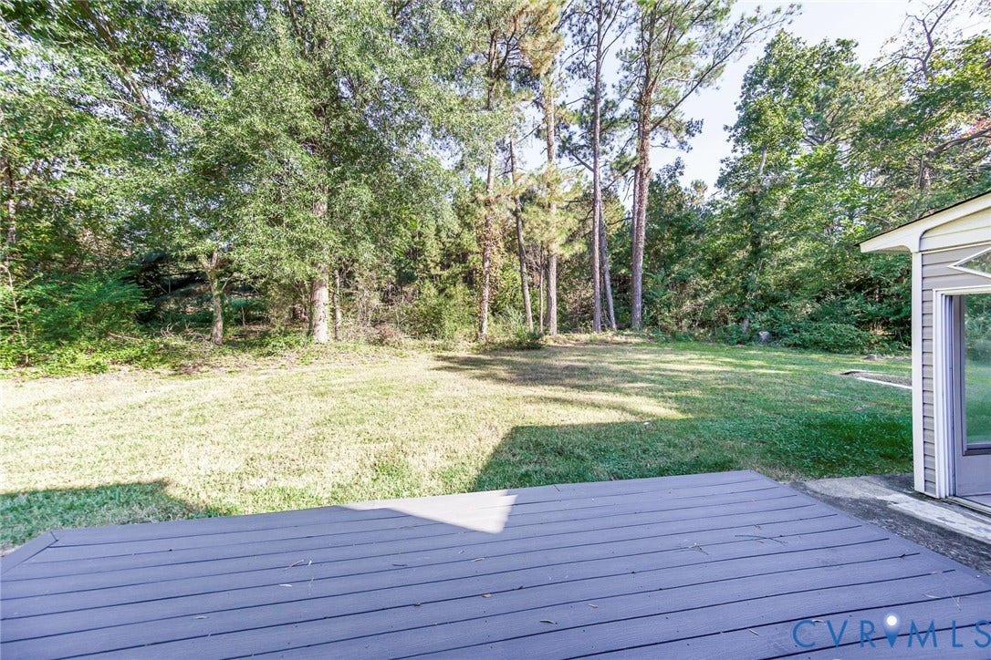4124 Cogbill Road, Ampthill, VA 23234 Rear exterior featuring a wood-finish deck, level lawn, and mature perimeter trees