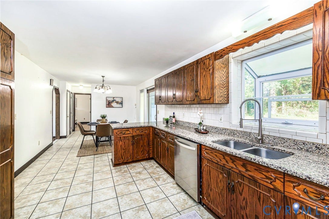 4124 Cogbill Road, Ampthill, VA 23234 Kitchen featuring stained wood cabinetry, stone-finish countertops, subway tile backsplash, stainless steel dishwasher, and a garden window above a dual-basin sink