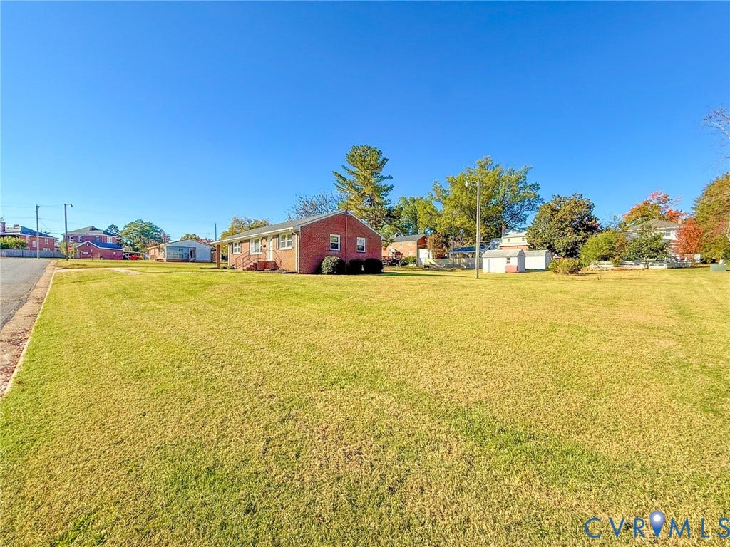 109 Rock Castle Avenue, Crewe, VA 23930 Single-story brick exterior featuring a sprawling lawn, mature trees, and detached storage structures