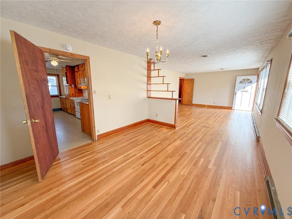 109 Rock Castle Avenue, Crewe, VA 23930 Open-concept interior featuring light-toned wood-finish flooring, a tiered open-frame wooden partition, a multi-light candelabra chandelier, and a solid wood entry door