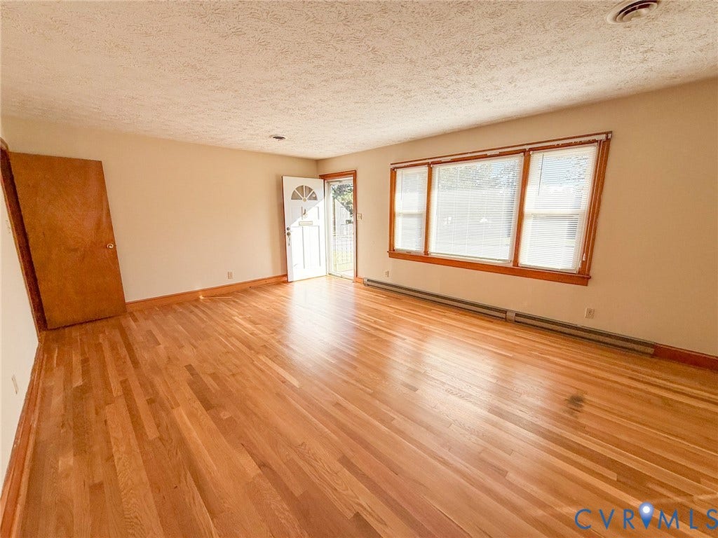 109 Rock Castle Avenue, Crewe, VA 23930 Interior space featuring polished wood-finish flooring, large triple-pane windows with wood-toned trim, and a solid wood entry door with a decorative glass panel