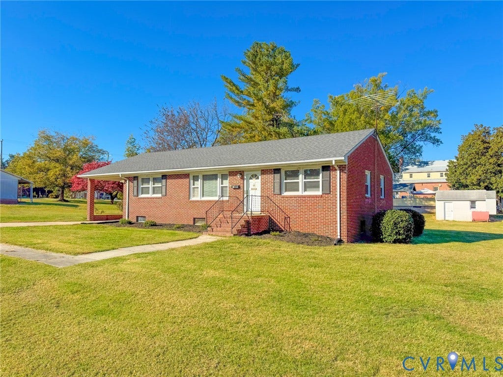 109 Rock Castle Avenue, Crewe, VA 23930 Single-story brick exterior featuring a covered front porch, grey shingle roof, iron railings, and a detached storage structure