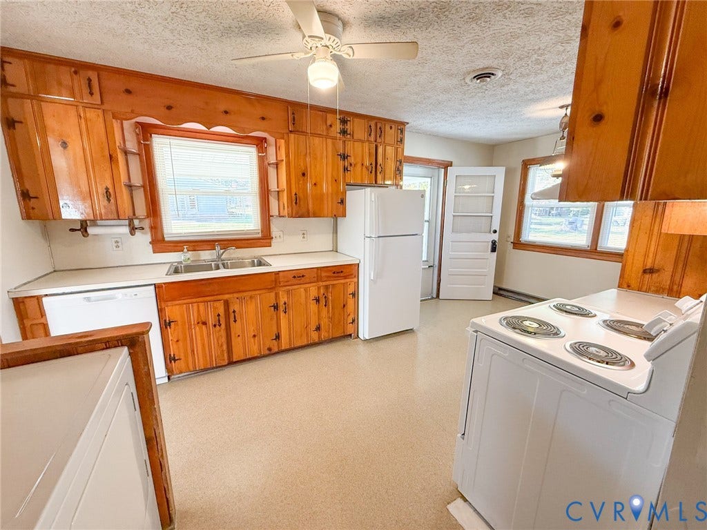 109 Rock Castle Avenue, Crewe, VA 23930 Kitchen featuring knotty pine cabinetry, a dual-basin stainless steel sink, solid-surface countertops, and a ceiling-mounted light fixture with a fan