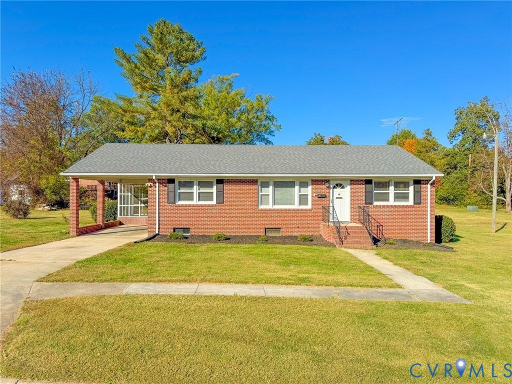 109 Rock Castle Avenue, Crewe, VA 23930 Brick exterior ranch home featuring a covered carport, pitched asphalt shingle roof, dark window shutters, and a front entry staircase with metal handrails