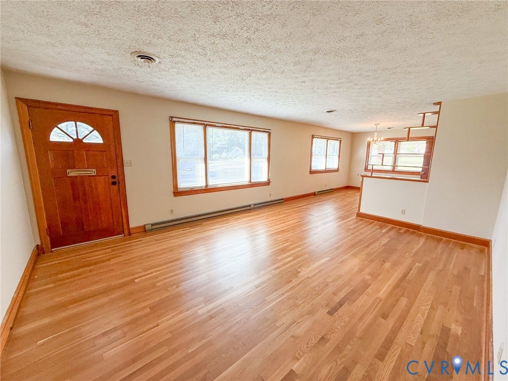 109 Rock Castle Avenue, Crewe, VA 23930 Interior space featuring wood-finish flooring, a wood-paneled front door with a decorative transom window, large picture windows, and a built-in room divider
