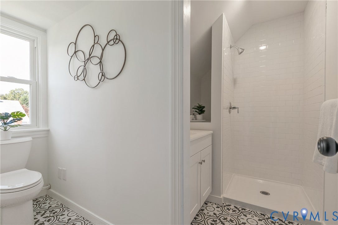 24 N Elm Avenue, Henrico, VA 23075 Bathroom featuring a shower stall with white subway tile surround, vanity with cabinetry, and patterned floor tile