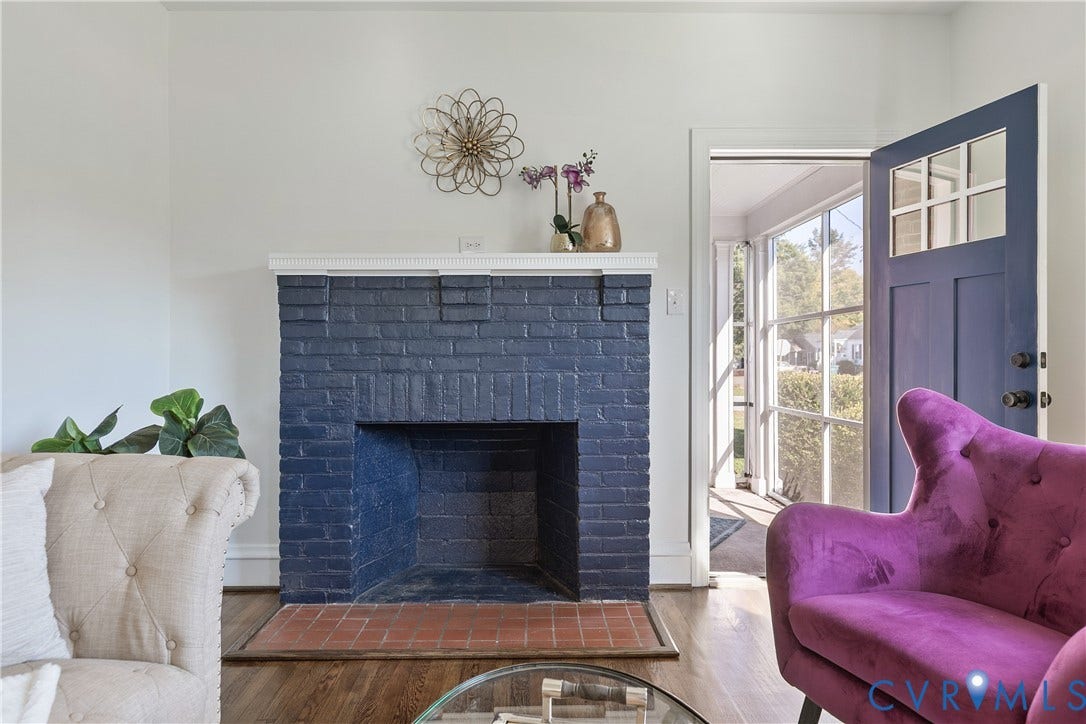 24 N Elm Avenue, Henrico, VA 23075 Painted brick fireplace with a white mantelpiece, terracotta hearth, wood-finish flooring, and a multi-pane glass entry door