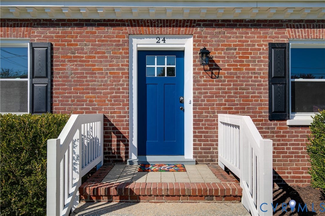 24 N Elm Avenue, Henrico, VA 23075 Red brick exterior featuring a blue front door with a six-pane window insert, decorative black shutters, white railings, and a brick-bordered stone stoop