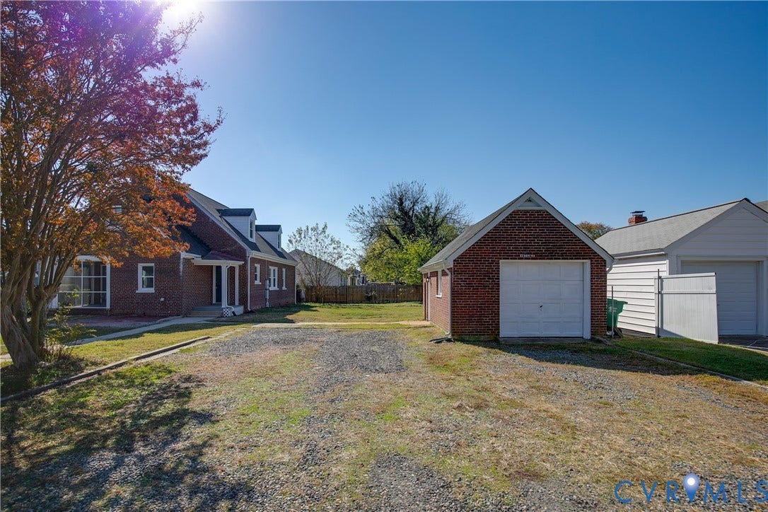 24 N Elm Avenue, Henrico, VA 23075 Brick exterior residence featuring a detached brick garage, gravel parking area, and mature landscaping