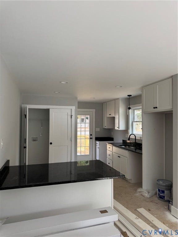 Kitchen featuring white shaker-style cabinetry, dark stone countertops, an integrated peninsula, recessed ceiling lighting, and a gooseneck faucet