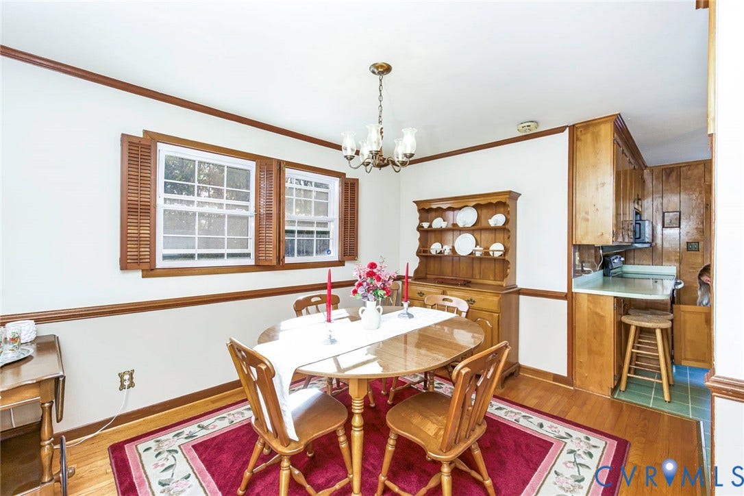 700 Lakeside Drive, Emporia, Emporia, VA 23847 Dining space featuring wood-finish flooring, wood-toned chair rail molding, dual windows with wood shutters, and a multi-arm chandelier